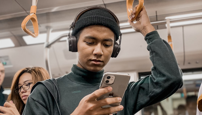 Homem mexendo no celular no metrô